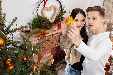 计划一对情侣把金星放在圣诞树顶上 装饰圣诞装饰树的装饰品呢新郎恋爱家庭新娘氛围气氛工艺邮政庆典符号背景图片
