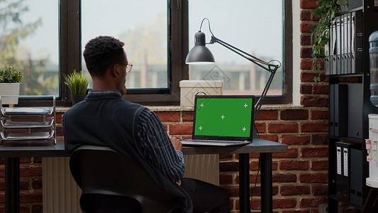 男性秘书分析启动办公室膝上型电脑的绿色屏幕图片