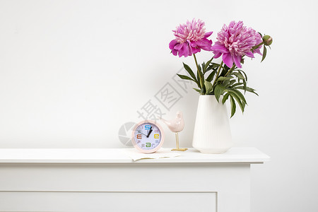 粉红色钟表红 粉红色的花瓶 在白花瓶在桌子 钟表和白色墙背景上背景