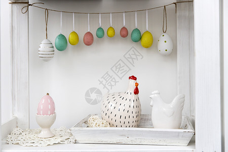 复活节海报内部的片段 为复活节装饰的儿童房 墙上的塑料鸡蛋花环 桌子上托盘上的陶瓷母鸡 您的文本的地方 复活节贺卡背景