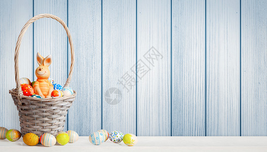 挎着篮子兔子复活节背景 木头背景上有丰富多彩的东方鸡蛋传统毛皮耳朵季节草地童年乐趣桌子动物庆典背景