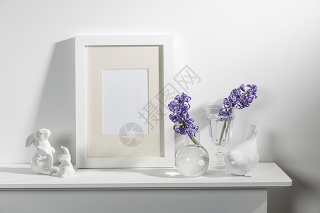 相框小素材大瓷碗里的白色风信子 书籍 野兔和鸟的雕像 一个空的相框放在壁炉上 靠着白色的墙壁 布局兔子装饰玻璃沙发塑像房间植物制品白墙陶瓷背景