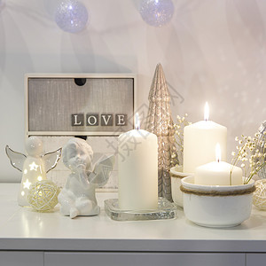 天使花环装饰圣诞节房子的概念 点燃蜡烛 园林 迪斯科舞团 白箱柜子上的天使雕像 文字放在何处柳条花瓶制品框架陶瓷小样塑像植物烛台托盘背景