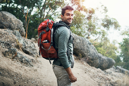 去野吧让我们去冒险吧 一个穿着背包的快乐年轻人的肖像 准备登山上山来着背景