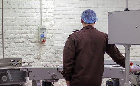 棕色的设备在巧克力工厂生产糖果 食品工业厂房 一名身穿制服的男工监督自动化传送带的生产过程 工厂工人师傅背景