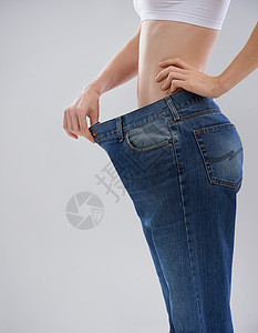 女人用长裤露出她的体重损失的一张照片被割伤了 她穿了一双大条裤子背景图片