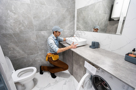 一个男人在浴室的柜子上 设置洗手盆下水道镜子卫生服务龙头陷阱修理工男人工作管子男性高清图片素材