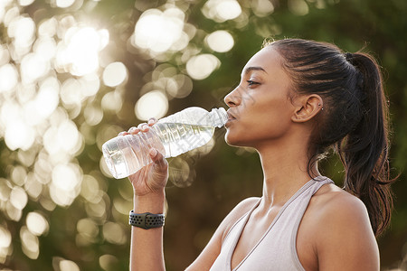 你可以喝当你需要补充能量时休息一下 一名运动型年轻女子在户外锻炼时喝水的镜头背景
