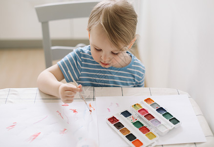 激发儿童潜能儿童在白桌上用水彩颜料绘画和绘画 开发儿童的创造潜能教育调色板爱好艺术家插图孩子们幼儿园家庭闲暇喜悦背景
