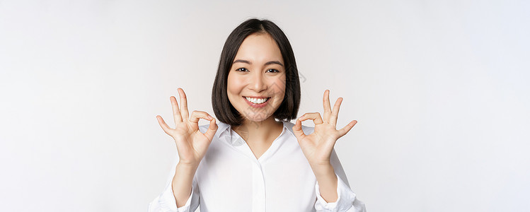 好物推荐头像特写亚洲女孩的头像 表现出好的 好的手势和满意的微笑 推荐 高兴 赞美和恭维 白色背景管理人员办公室女士公司工作室成人商业冒充人背景