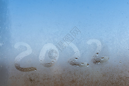 2022国庆节宣传展板在雾中窗口上的手写单词 2022面具季节编号疾病玻璃刻字手绘雨滴数字蓝色背景