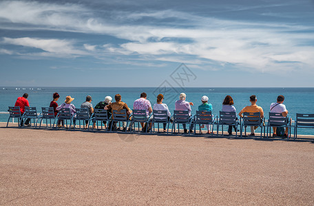 利古里亚人人们坐在法国尼斯堤防上著名的蓝色椅子上 看着利古里亚海的蔚蓝海水 宁静 晚年 休息 老年人 地平线 社会季节气候环境景观风景假期背景