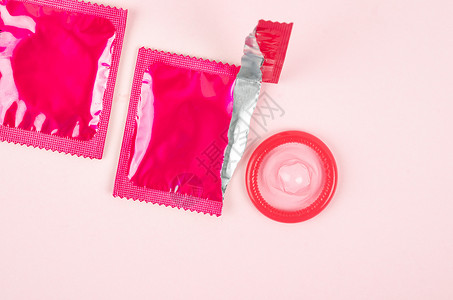 粉红色在粉红背景上打开了避孕套和保险套商品摄影保健医学疾病风险避孕乳胶主题包装背景
