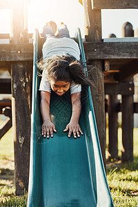 潜入 头先下 拍到一个可爱的小姑娘 在公园的滑板上玩耍背景