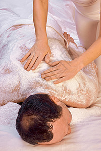 皮一下字体设计女医生用盐做仪式 用盐擦一个躺着的男人的背部 放松一下女性沉思疗法人皮和声洗澡享受治疗师皮肤两个人背景