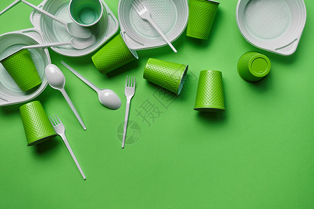 一次性塑料餐具在绿色背景的白色塑料一次性餐具与拷贝空间 野餐用具的概念 顶视图 选择性的焦点 特写服务环境桌子早餐盘子外卖用具工具烹饪炙烤背景