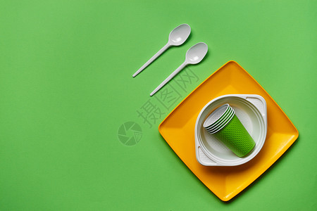 塑料桌子在绿色背景的五颜六色的塑料一次性餐具与拷贝空间 野餐用具的概念 顶视图 选择性的焦点 特写餐饮配件派对团体杯子盘子用具桌子圆圈环背景
