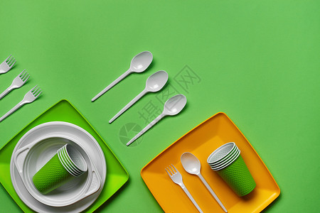 在绿色背景的五颜六色的塑料一次性餐具与拷贝空间 野餐用具的概念 顶视图 选择性的焦点 特写午餐外卖玻璃餐饮厨房商品工具圆圈产品盘背景图片