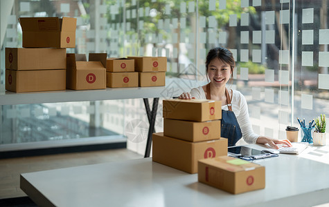 box创业小企业自由职业者 在家办公室工作的肖像年轻女性 BOX 智能手机 笔记本电脑 在线 营销 包装 交付 b2b 中小企业 电子背景