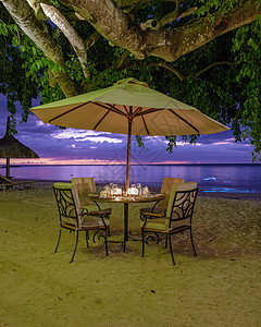 晚上喝毛里求斯海滩日落 豪华餐厅 有雨伞和椅子在沙滩上吃晚饭环境旅行海滩夫妻婚礼庆典海岸玻璃浪漫蜡烛背景