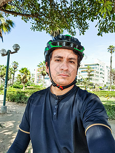 钢铁侠炫酷海报穿着黑色自行车服装的年轻英俊骑自行车者 在公园中戴头盔背景