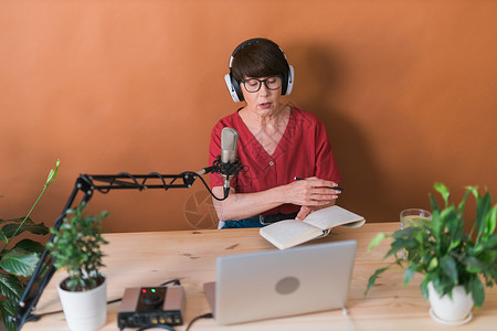中年女电台主持人为在线节目制作播客录音  广播和 DJ 概念工作室耳机公告笔记本商业音乐打碟机企业家工作收音机背景图片