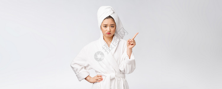 白色浴袍年轻女性的美容肖像显示并指向空空间复制 浴袍中的亚洲美温泉成人治疗浴衣成功快乐微笑护理身体广告背景