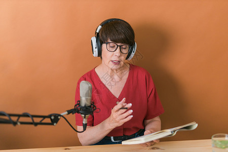 中年女电台主持人为在线节目制作播客录音  广播和 DJ 概念互联网播音员技术立体声工作室办公室商业播送工作女性背景图片