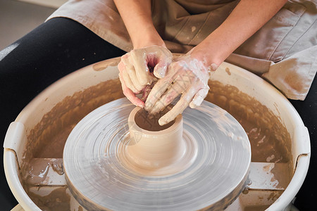 车轮转动女人在轮子上制作陶瓷陶器 创造陶瓷器皿 妇女工作 工艺的概念背景