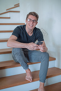笑笑的家伙在智能手机上读信息快乐服务楼梯家庭电话帮助装修互动公寓房子图片