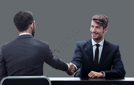 与坐在桌边的商界人士握手面试职场经理协议微笑套装男人会议领导管理人员图片