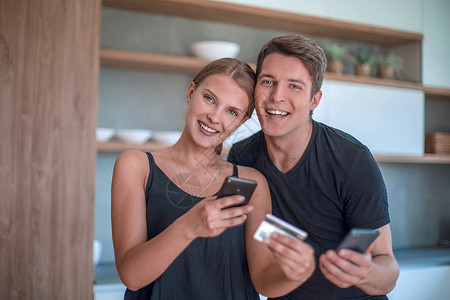 年轻家庭在线支付智能电话费以及快乐网络顾客互联网厨房夫妻男人营销女性电子商务背景