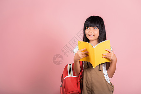 黄色小背包10岁的亚洲小孩持有和阅读黄色书本 十岁教育学习学校青少年童年乐趣小说女孩女性图书馆背景