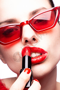 红太阳镜中的黑褐色女人用红口红 红指甲 白底漆嘴唇图片