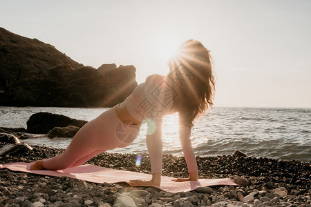 卵石垫中年漂亮的女人 一头黑发 在卵石滩海边的瑜伽垫上用戒指做普拉提 女性健身瑜伽概念 健康的生活方式 和谐与冥想训练成人女孩健身房运背景