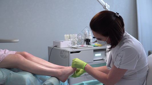 足科医生为手术准备腿部 她用餐巾擦脚 在修脚沙龙的指甲护理洗高清图片素材