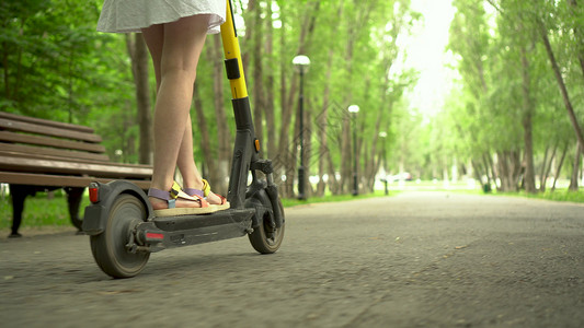 出租滑板车穿着白裙子的年轻女子骑着共用电动摩托 在公园里工具女性自行车城市运输学生街道游客骑术手机背景