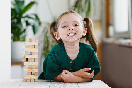 微笑快乐的学龄前女孩玩积木 待在家里 在游戏中有趣而快乐 白人孩子喜欢这个游戏背景图片