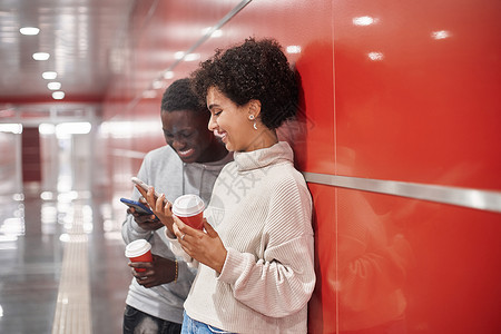 有智能手机的年轻夫妇等待地铁列车图片