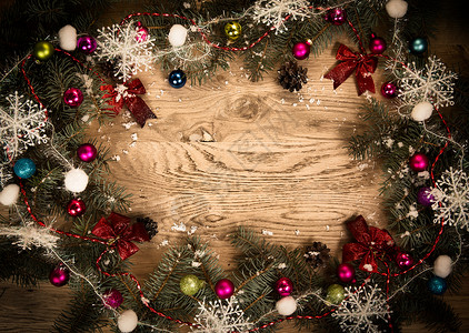 木制地板上的绿壁树枝 边上漆黑 有圣诞装饰品雪花季节性丝带小枝假期桌子快乐风格传统边框背景图片