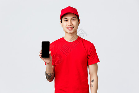 装着红色制服 帽子和T恤衫的微笑送货员 展示移动电话屏幕 建议下载奖品申请单等信息工具为购买奖金而下载咨询应用程序运输房子手机互背景