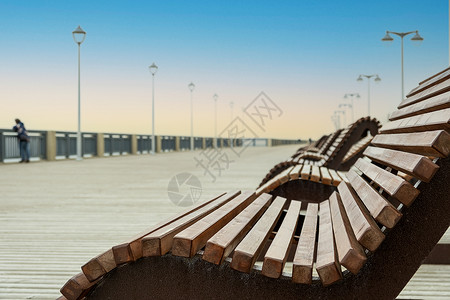 木制长椅在空海中走着的太阳休息者城市海岸旅游长廊栏杆路面旅行全景海岸线天气背景