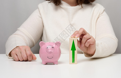 粉色向右箭头粉红陶瓷小猪银行和用箭头的木块 在银行存款中利息增加的概念背景
