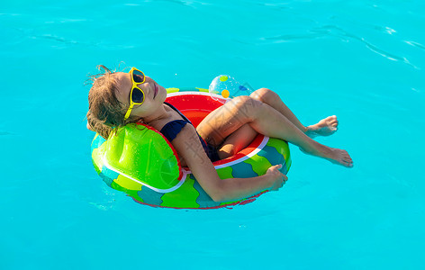 游泳玩具圆圈中的孩子在游泳池里游泳 有选择的焦点假期乐趣太阳喜悦西瓜飞溅幸福戒指童年闲暇背景