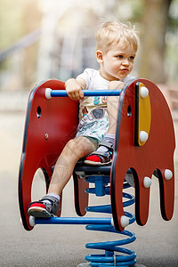 假期余额不足一个可爱男孩的肖像 在一个操场上 在红色的大象设计 平衡摆动微笑弹簧幼儿园娱乐闲暇游戏假期乐趣金发女郎骑术背景