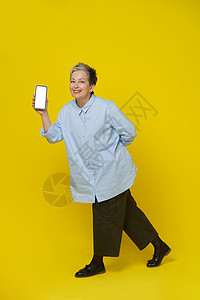 金融app启动页穿着蓝衬衫和棕色长裤的漂亮女性被黄色背景隔离 Mocto app广告 Mockup产品布置撰稿人金融上网人士白发退休网上购物药片背景