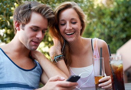 二十一世纪的社会化 可爱的青少年夫妇共享一个 MP3 播放器 边喝边听音乐背景图片