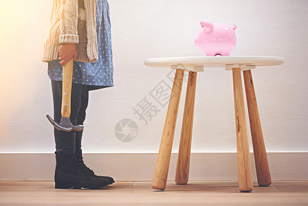 有个小女孩拿着锤子站在她的猪银行旁边 她的储蓄很早就开始起步了图片
