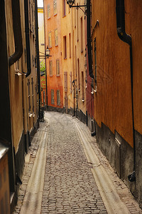 砖砌小巷欧洲旅游城市中安静 空荡荡的鹅卵石街道 乡村小镇的一条狭窄小巷 周围环绕着高大的公寓楼或红房子 隐藏着传统建筑的小街背景