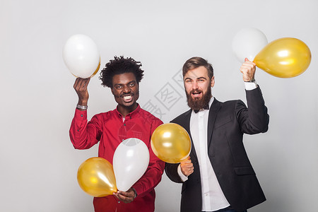 快乐的朋友们庆祝生日 拿着金和白气球 举起手来微笑背景图片